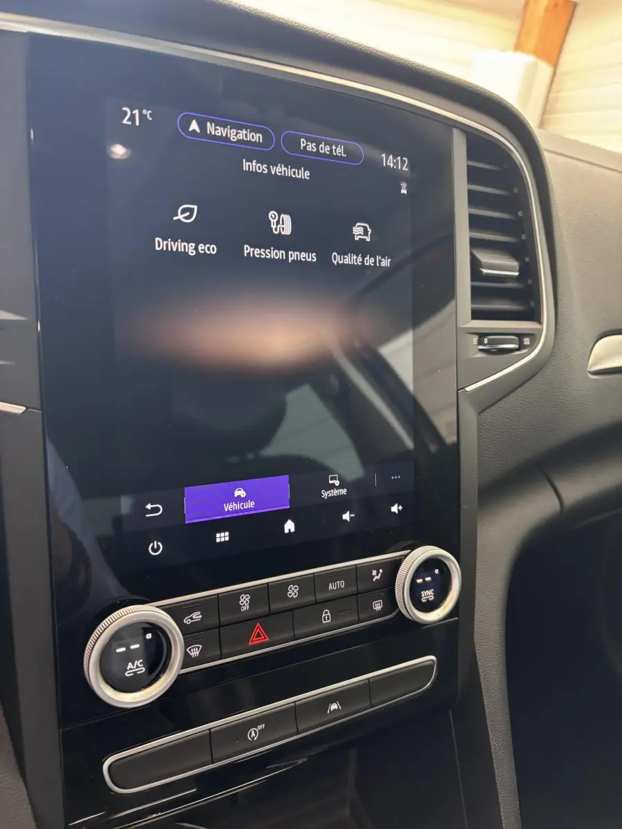 Vue rapprochée de l'écran tactile central et des commandes de climatisation dans l'habitacle noir de la Renault Mégane bleu 2023.