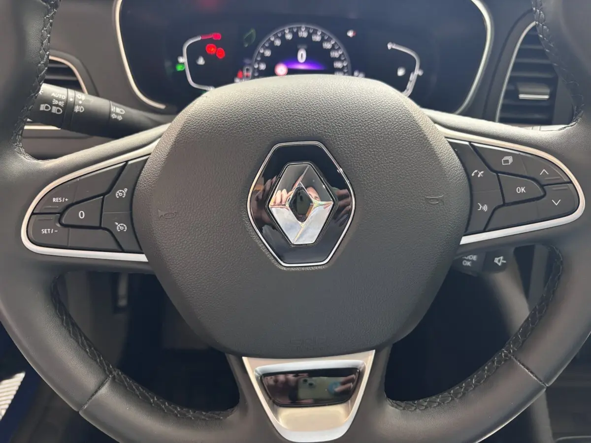 Volant noir de Renault Megane 2023 techno Blue dCi 115 EDC avec commandes multifonctions et tableau de bord numérique.