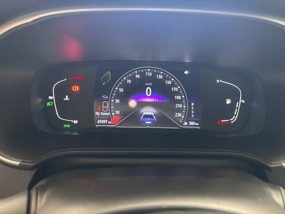 Tableau de bord numérique de la Renault Mégane 2023 bleu, affichant vitesse, jauges et alertes au centre de l'habitacle.