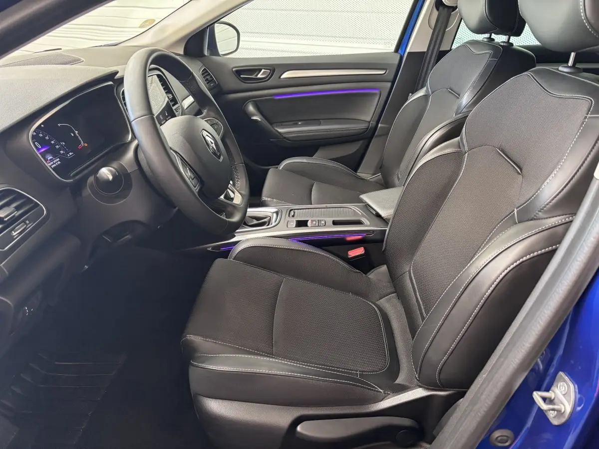 Intérieur avant droit de la Renault Mégane bleu 2023, sièges noirs avec éclairage d'ambiance violet et tableau de bord digital.