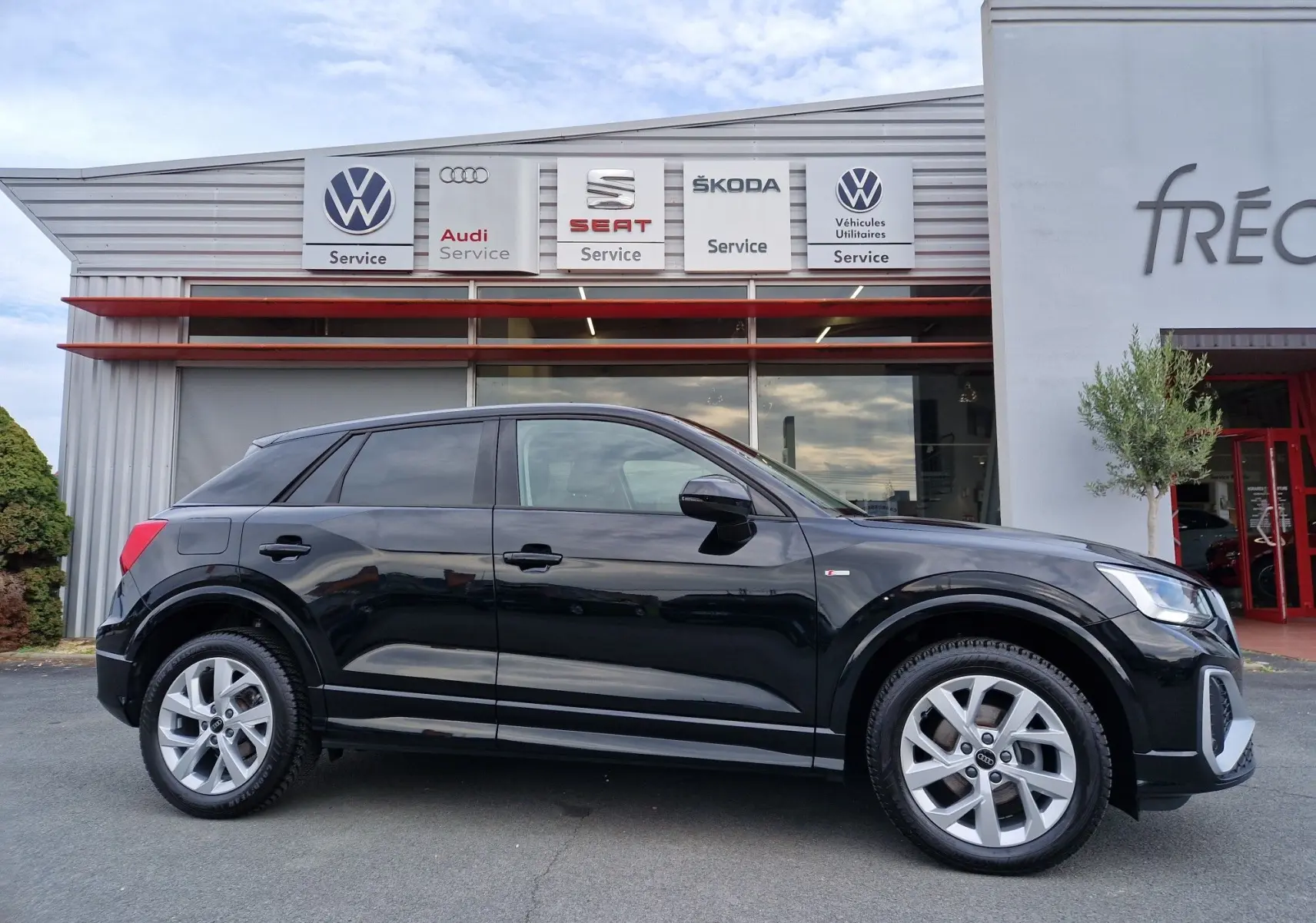 Audi Q2 35 TFSI noir mito metal en vue profil côté gauche, jantes alliage et calandre distinctive visibles.