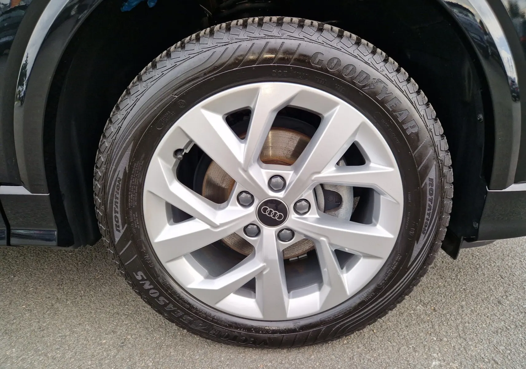 Gros plan sur la roue avant droite d'un Audi Q2 noir mito metal avec jante argentée et pneu Goodyear.