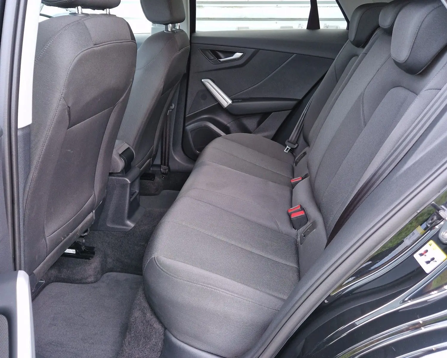 Vue intérieure côté droit sur la banquette arrière noire tissu d'un Audi Q2 35 TFSI 2023 noir mito metal.