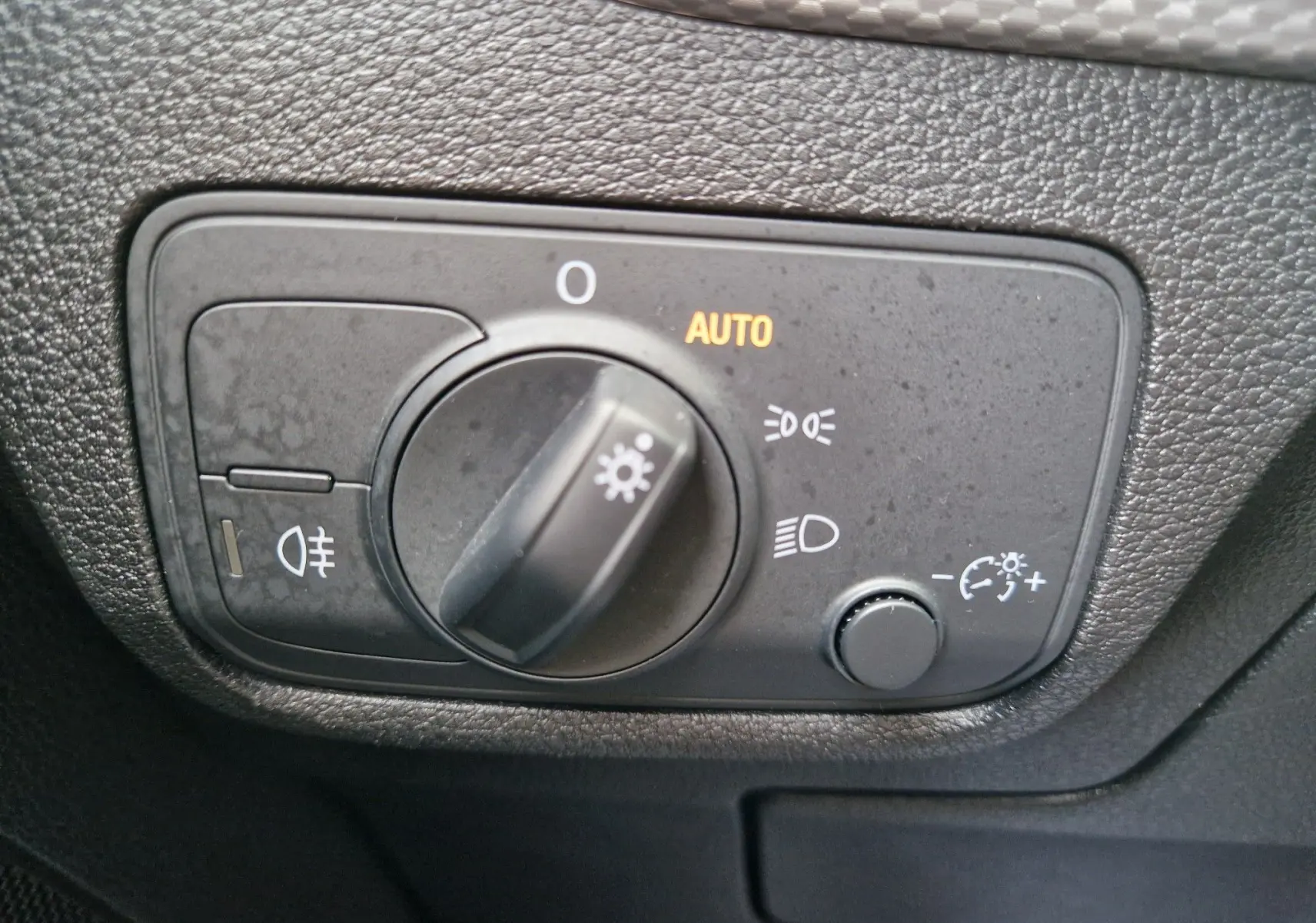 Gros plan sur le sélecteur de phares avec mode automatique du tableau de bord noir d'un Audi Q2 2023 noir mito metal.