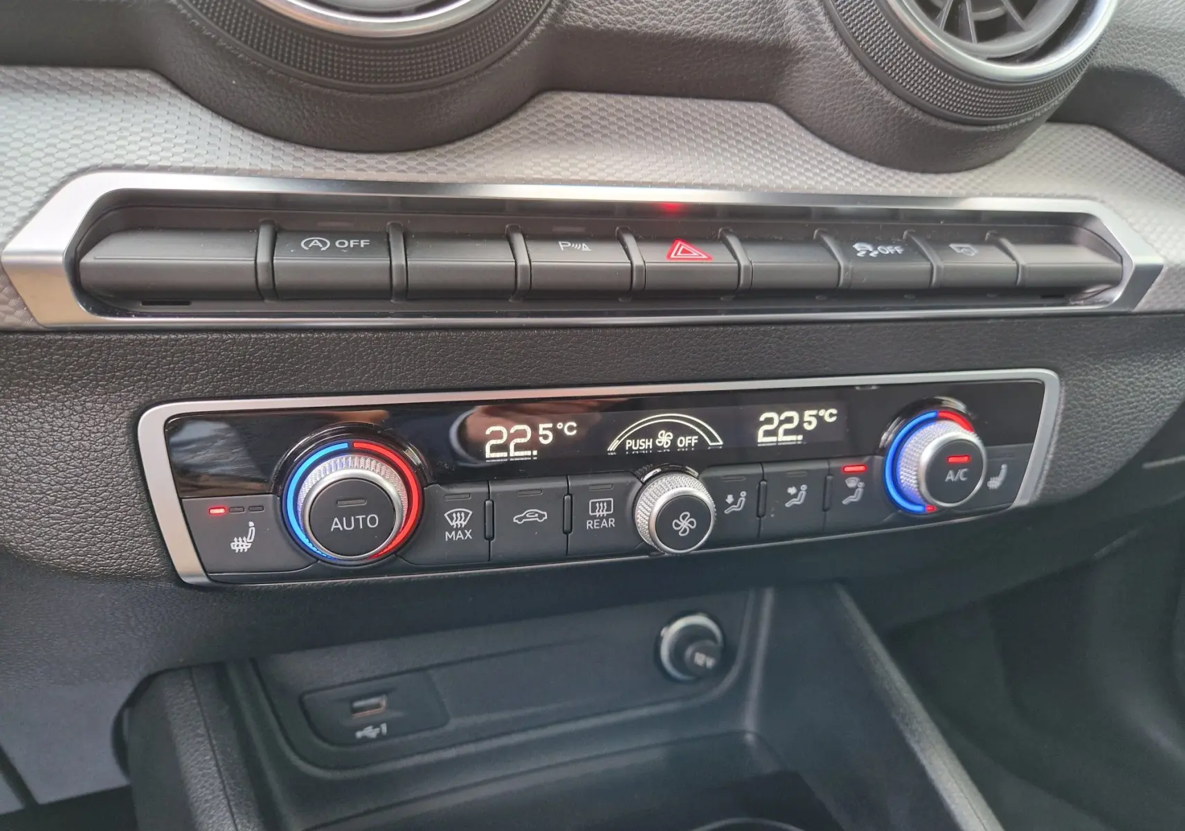 Gros plan sur la console centrale de l'Audi Q2 2023, avec climatisation automatique et commandes en noir et chrome.