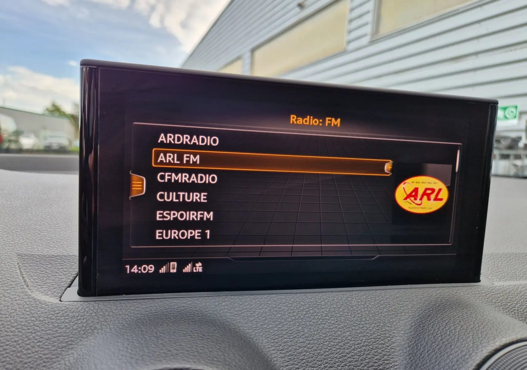 Écran central de l'Audi Q2 35 TFSI 2023 affichant les stations radio FM avec tableau de bord noir texturé visible.