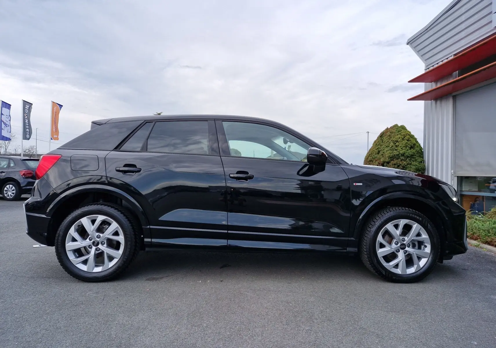 Audi Q2 35 TFSI noir mito metal vue de profil côté gauche, jantes alliage 17 pouces et lignes dynamiques.