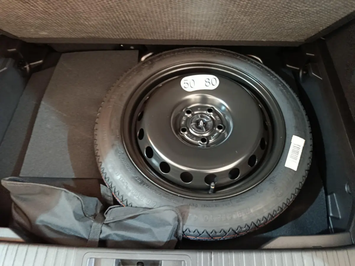 Vue rapprochée de la roue de secours noire dans le coffre du Renault Captur blanc techno E-Tech 2025.