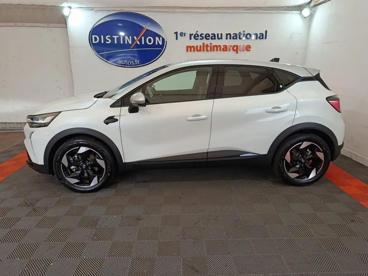 Profil côté gauche du Renault Captur blanc 2025 en version techno E-Tech full hybrid 145, avec jantes noires et détails noirs contrastants.