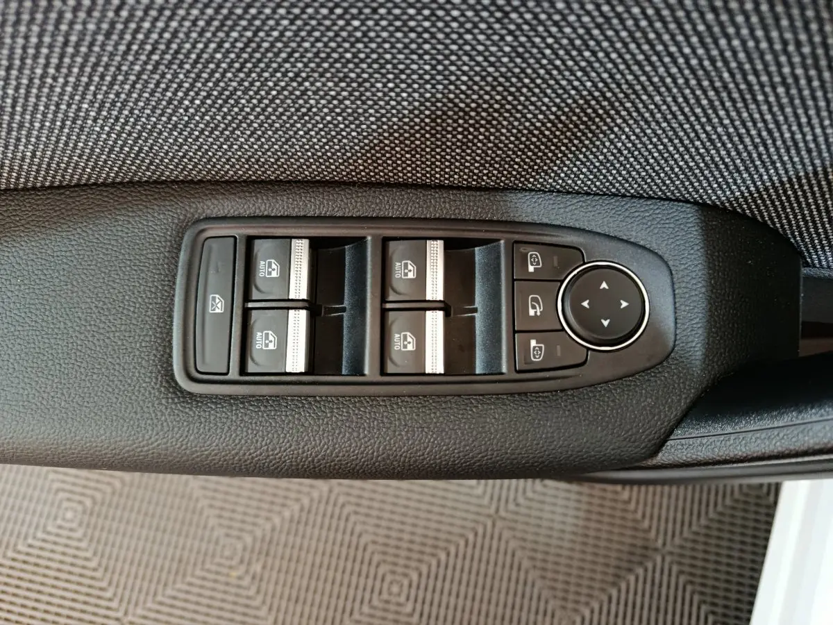 Commande des vitres électriques et réglage des rétroviseurs sur la porte côté conducteur du Renault Captur blanc 2025.