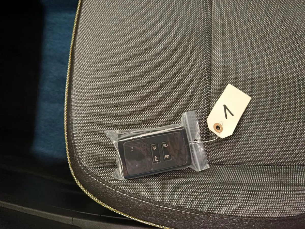 Gros plan sur la clé noire emballée posée sur un siège tissu gris foncé du Renault Captur blanc 2025.