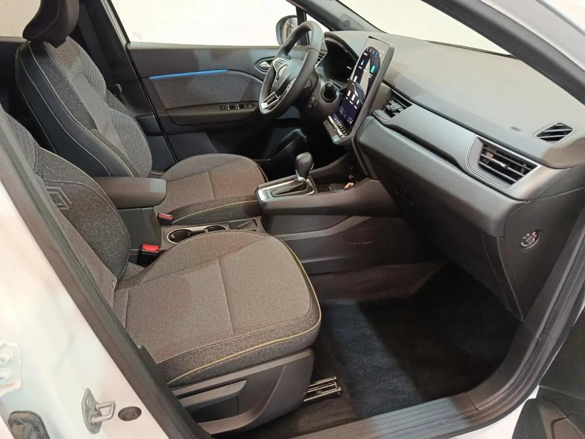 Intérieur avant droit du Renault Captur blanc 2025, sièges tissu gris et écran tactile vertical au tableau de bord.