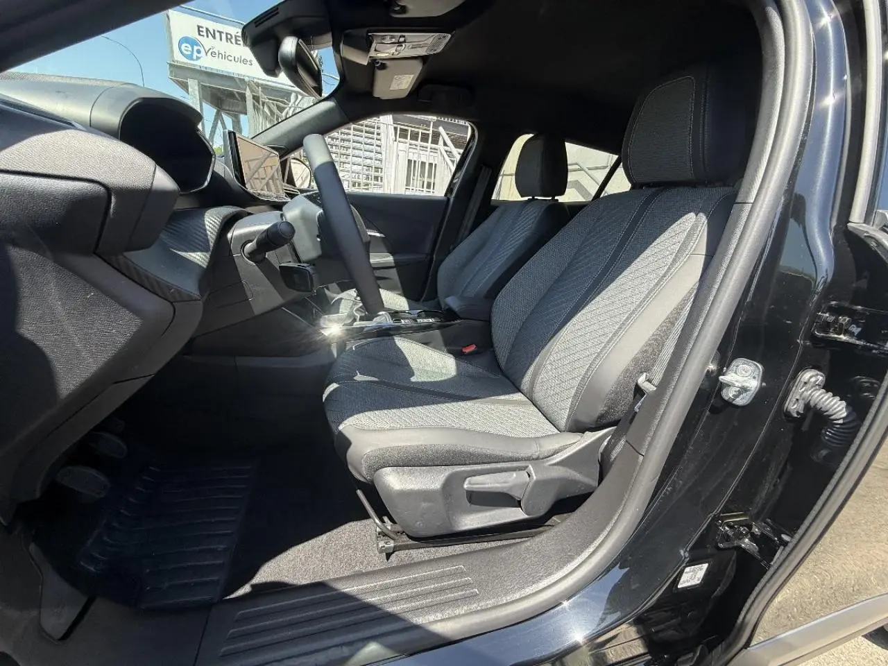 Intérieur du Peugeot 2008 2025 noir perla, vue côté gauche avant montrant les sièges tissu et le tableau de bord.