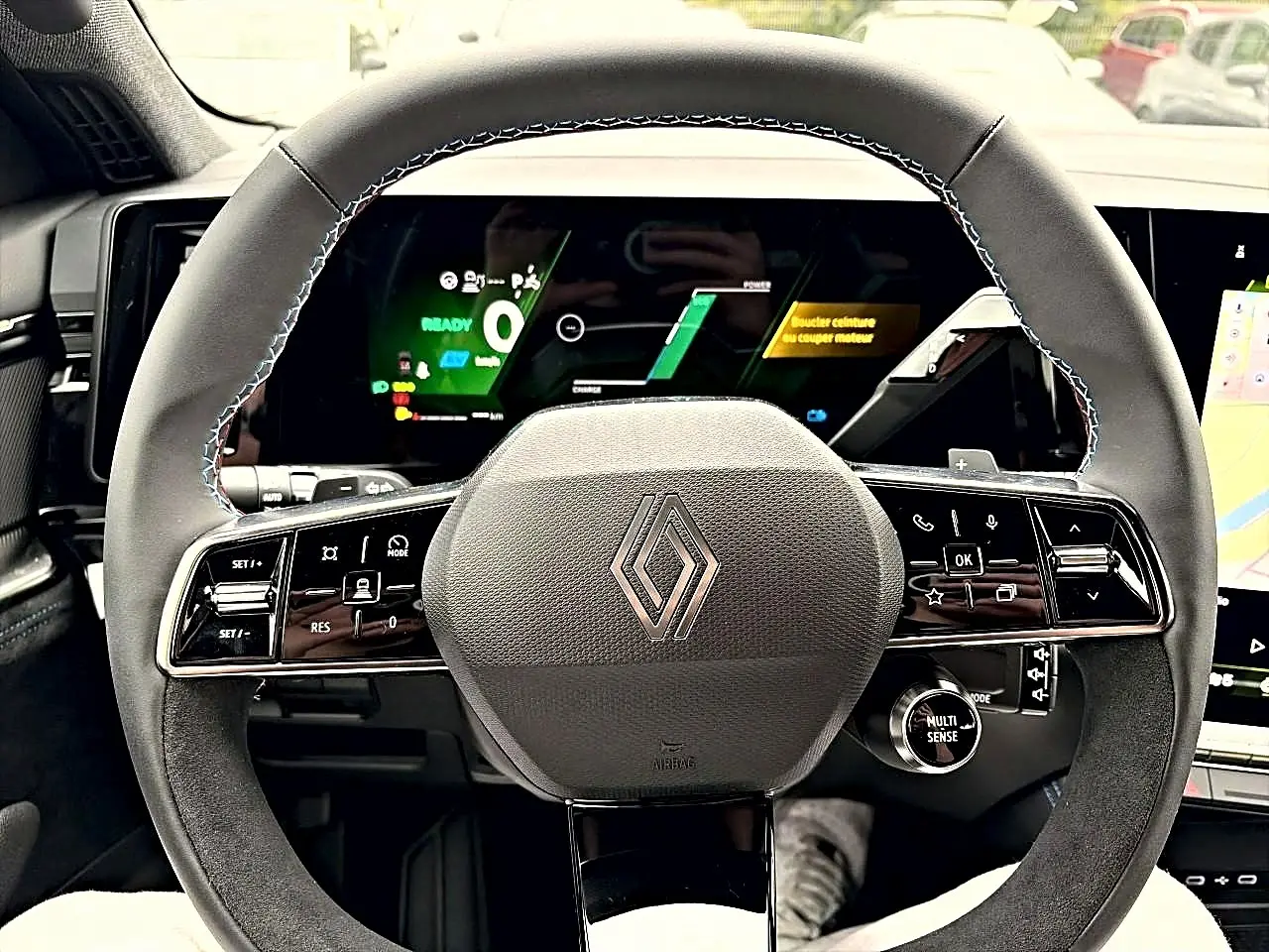 Vue rapprochée du volant gris et noir du Renault Austral 2026 avec commandes multifonctions et écran numérique en arrière-plan.
