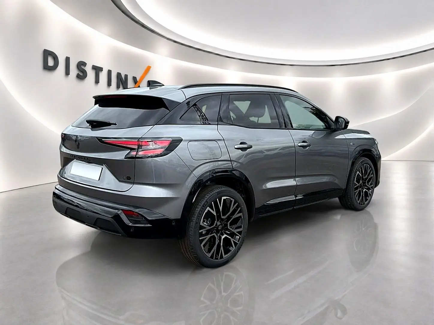 Vue 3/4 arrière droite du Renault Austral gris schiste avec jantes alu noires et toit noir contrasté dans un showroom.