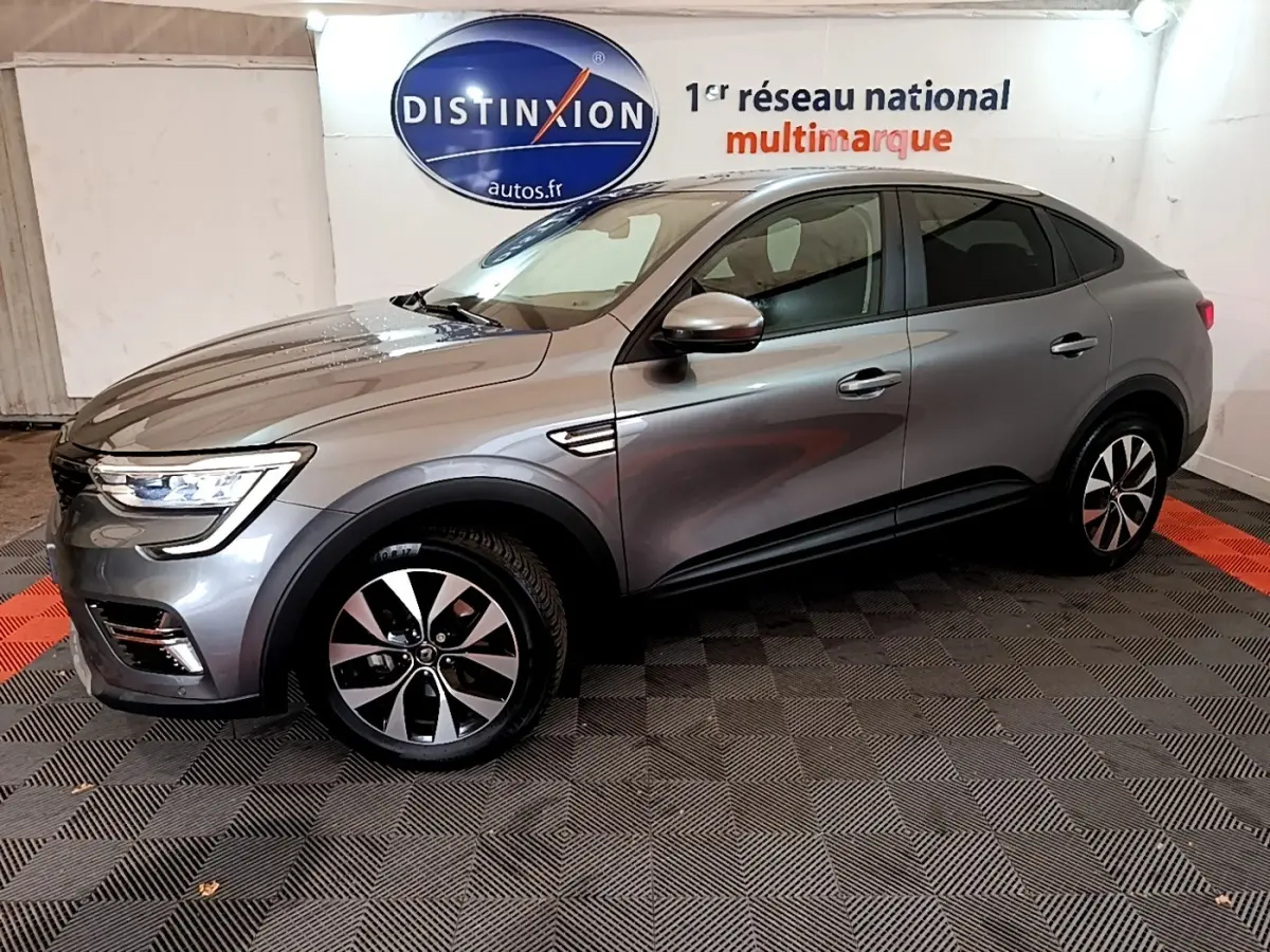 Renault Arkana Business E-TECH 145 gris foncé vu de profil côté gauche dans un showroom avec logo Distinxion en arrière-plan