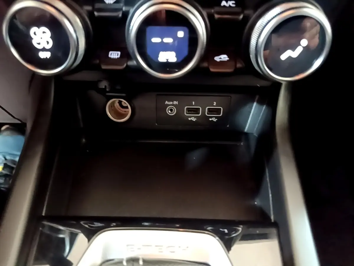 Vue rapprochée de la console centrale du Renault Arkana Business E-TECH 145, avec commandes de climatisation et ports USB visibles.
