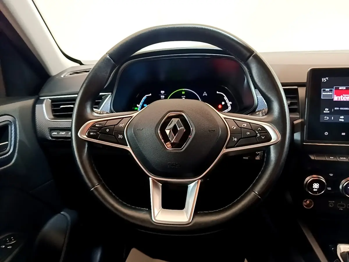 Volant en cuir noir avec logo Renault au centre, tableau de bord numérique et écran tactile à droite dans Renault Arkana Business E-TECH.