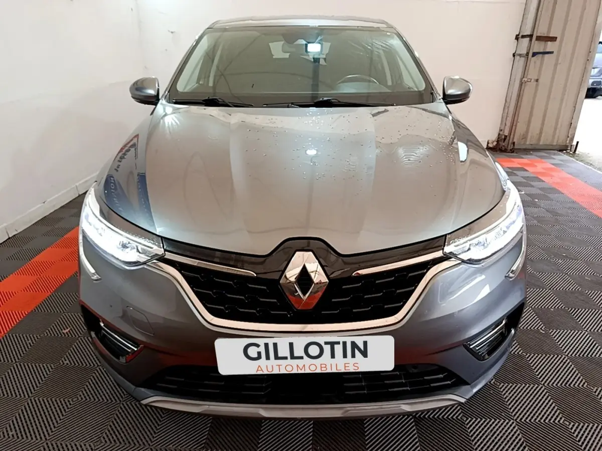 Vue frontale d'un Renault Arkana Business E-TECH 145 gris foncé avec phares LED allumés en intérieur.