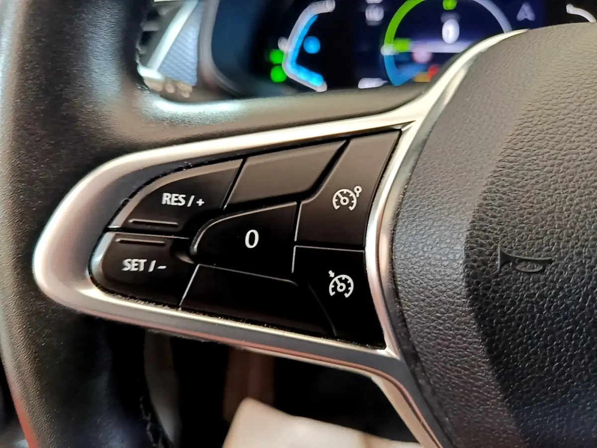 Gros plan sur les commandes du régulateur de vitesse au volant cuir du Renault Arkana Business E-TECH gris foncé 2022.
