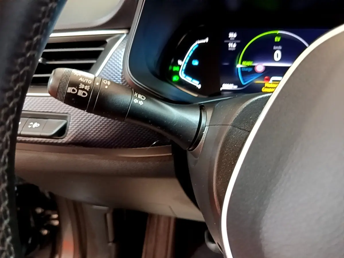 Gros plan sur la manette de phares à gauche du volant et le combiné d'instruments numérique du Renault Arkana Business E-TECH 145.