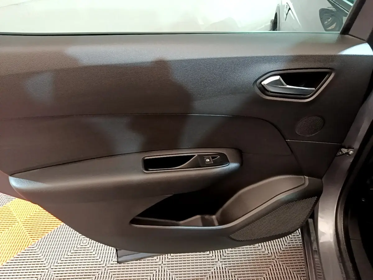 Gros plan sur la porte intérieure côté droit du Renault Arkana Business E-TECH 145 gris foncé, avec poignée et commande de vitre.