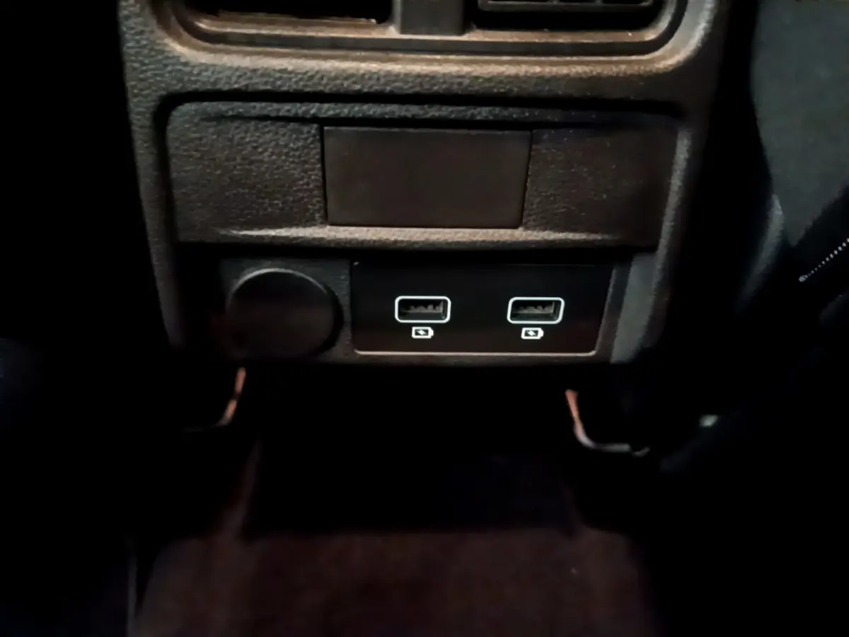 Prise USB double et prise 12V noire sous la console centrale du Renault Arkana Business E-TECH 145 gris foncé.