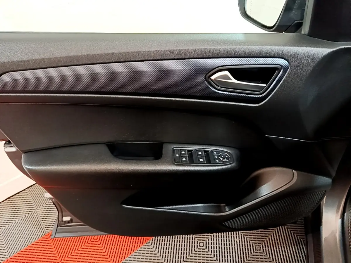 Vue intérieure côté gauche de la porte conducteur du Renault Arkana Business E-TECH 145 avec commandes électriques et poignée argentée.