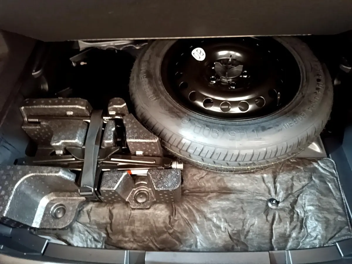 Vue du coffre ouvert d'une Renault Arkana Business E-TECH 145 2022, montrant la roue de secours et le kit de réparation.