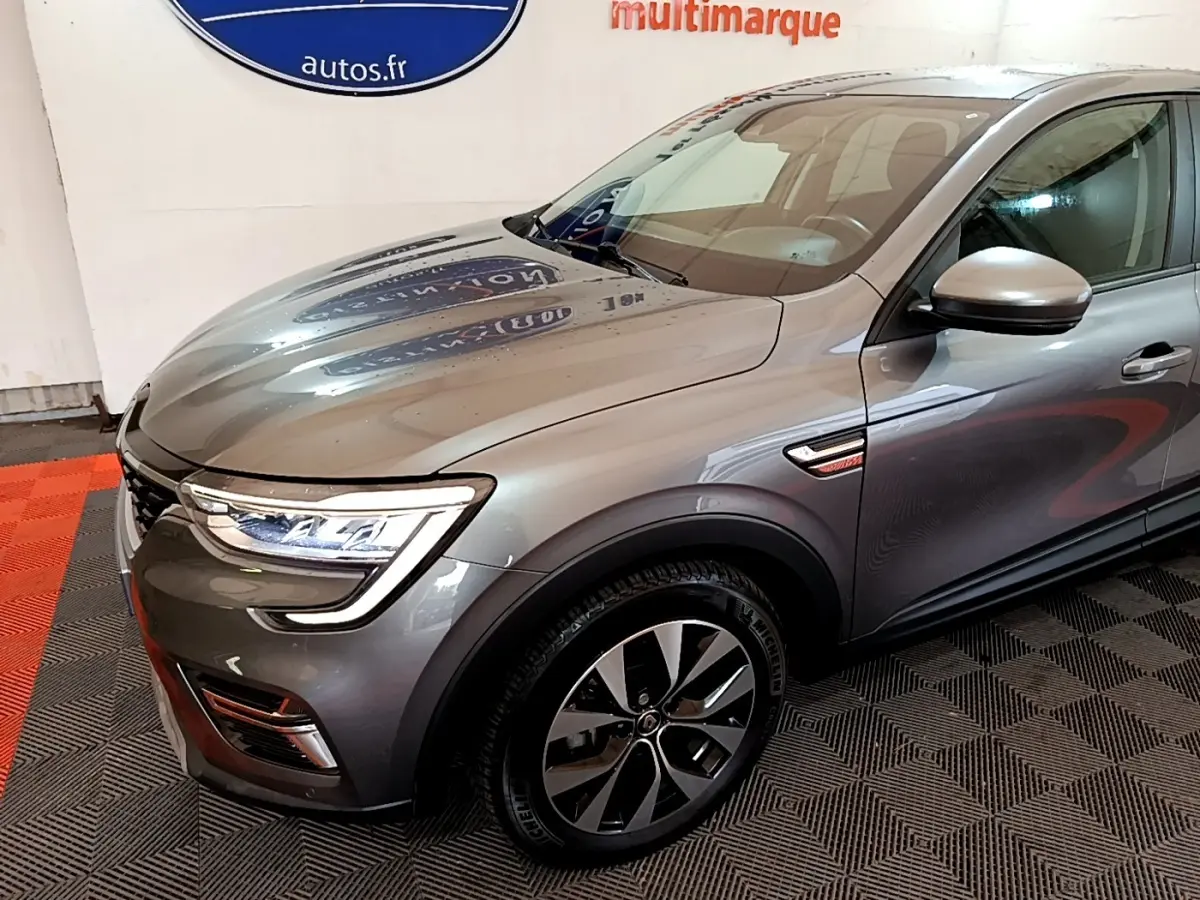 Vue 3/4 avant droit d'un Renault Arkana Business E-TECH gris foncé avec jantes alliage et feux LED distinctifs.