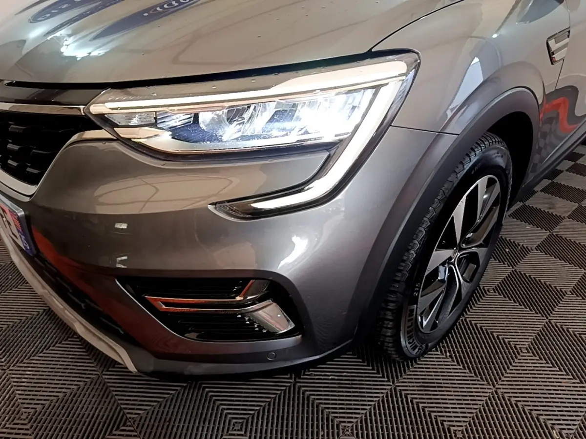 Gros plan sur l'avant droit gris foncé du Renault Arkana Business E-TECH 145, mettant en valeur le phare LED et la roue.