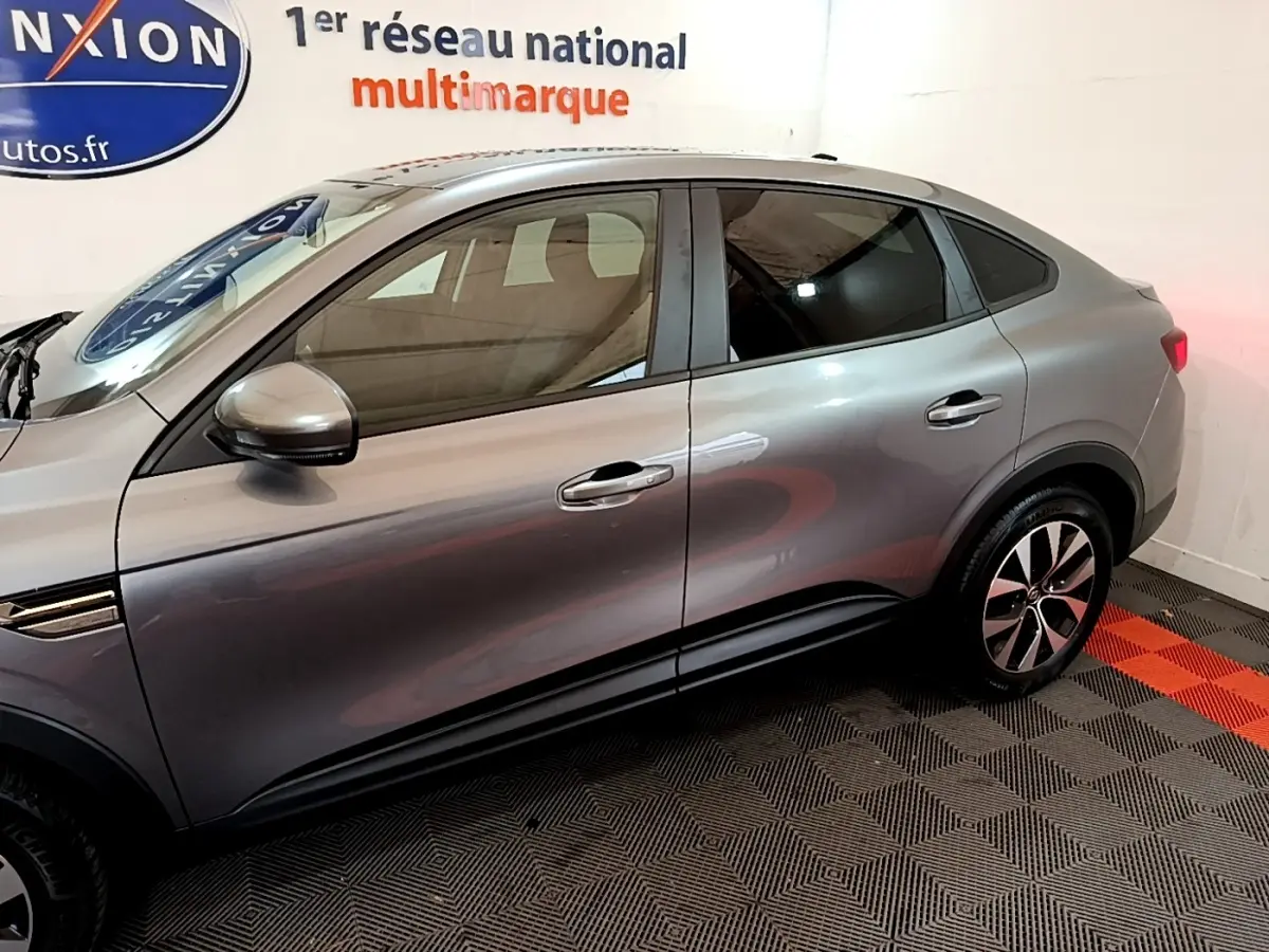 Profil côté gauche d'un Renault Arkana Business E-TECH 145 gris foncé avec jantes alliage et rétroviseurs intégrés.