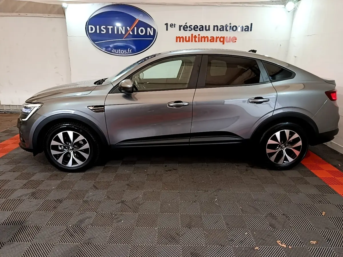 Profil côté gauche d'une Renault Arkana Business E-TECH 145 gris foncé, avec jantes alliage et lignes fluides du SUV coupé.
