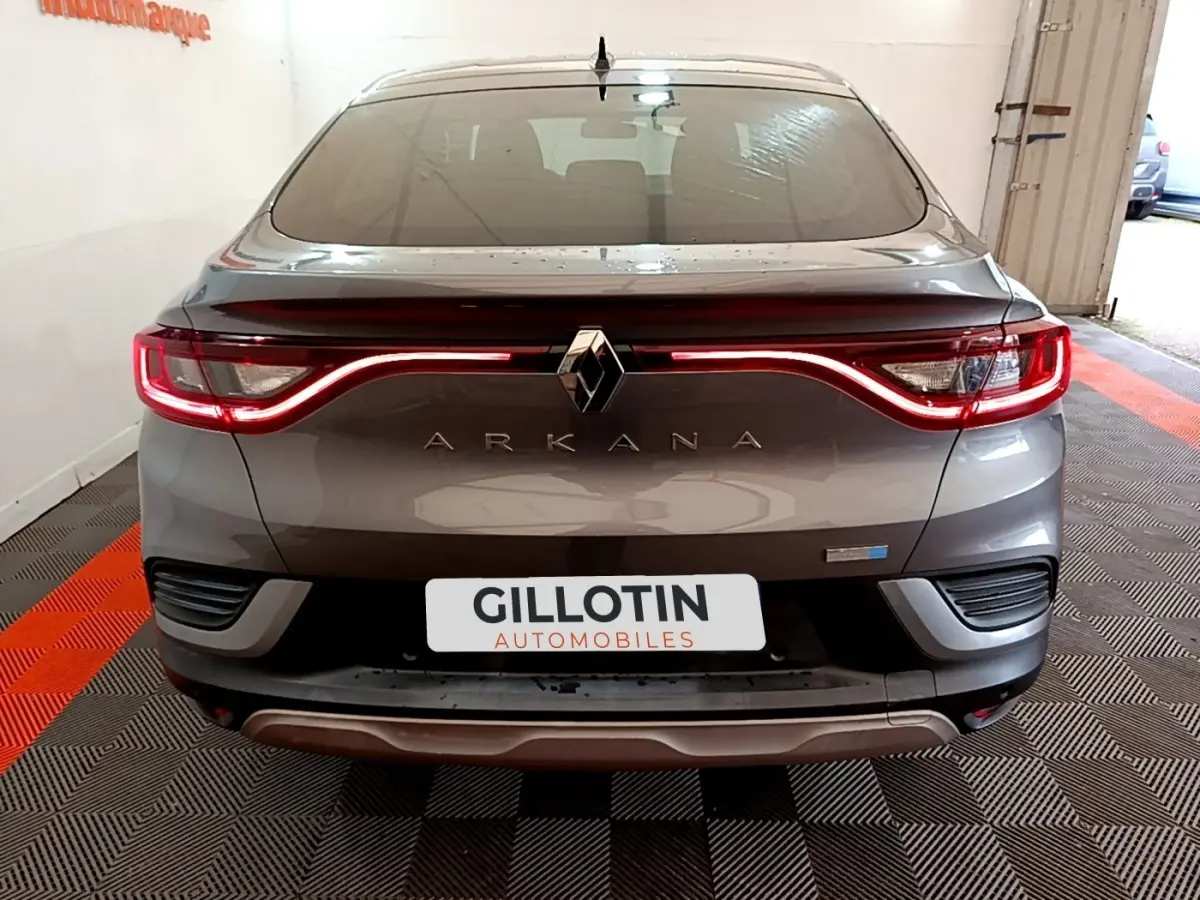 Vue arrière d'un Renault Arkana gris foncé avec feux LED en forme de vague et logo central lumineux.