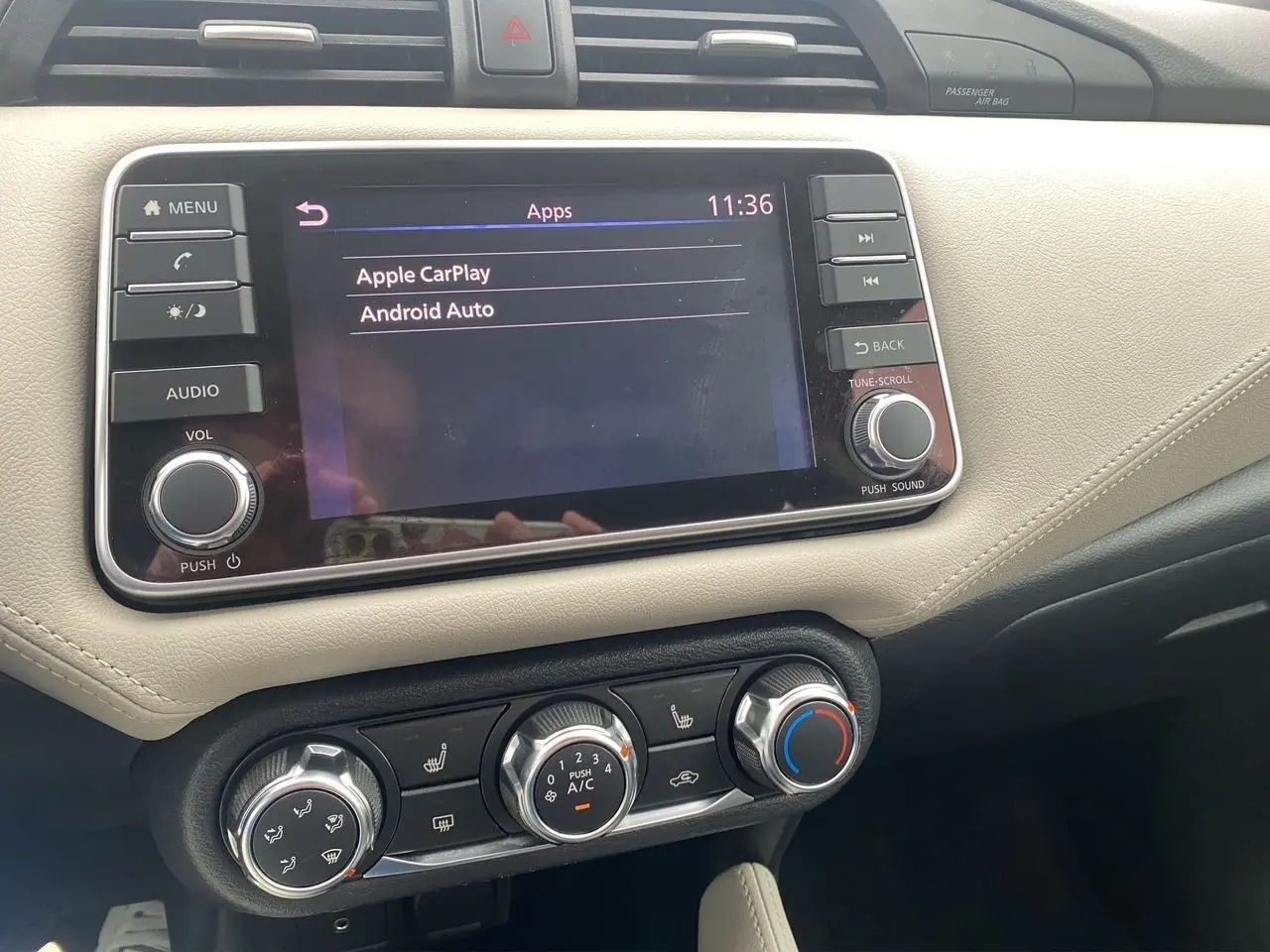 Vue rapprochée de la console centrale de la Nissan Micra 2022 avec écran tactile et commandes de climatisation beige et noir.