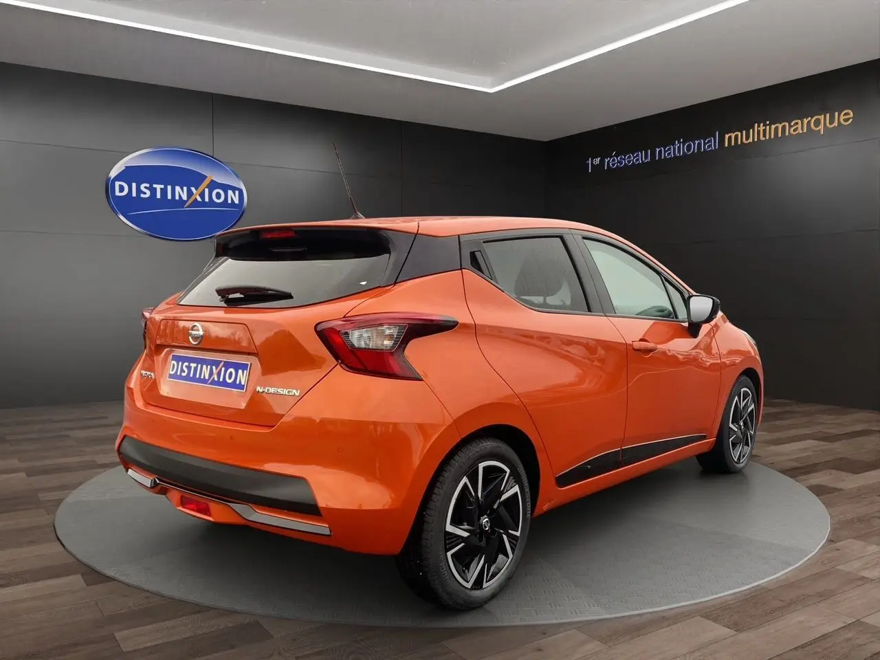 Vue 3/4 arrière droite d'une Nissan Micra 2022 orange Energy avec jantes noires et toit noir en showroom.