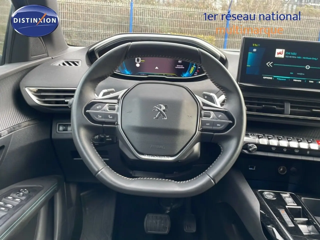 Vue intérieure centrée sur le volant et le tableau de bord numérique du Peugeot 3008 hybride 2024, finition noire.