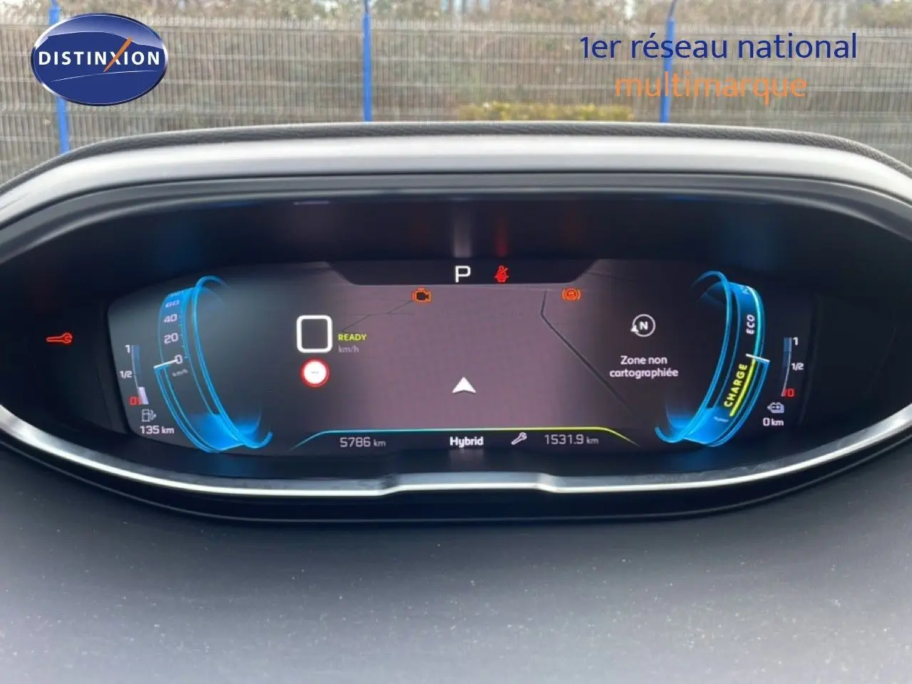 Vue rapprochée du tableau de bord numérique du Peugeot 3008 hybride, affichant la charge et la vitesse en mode prêt.