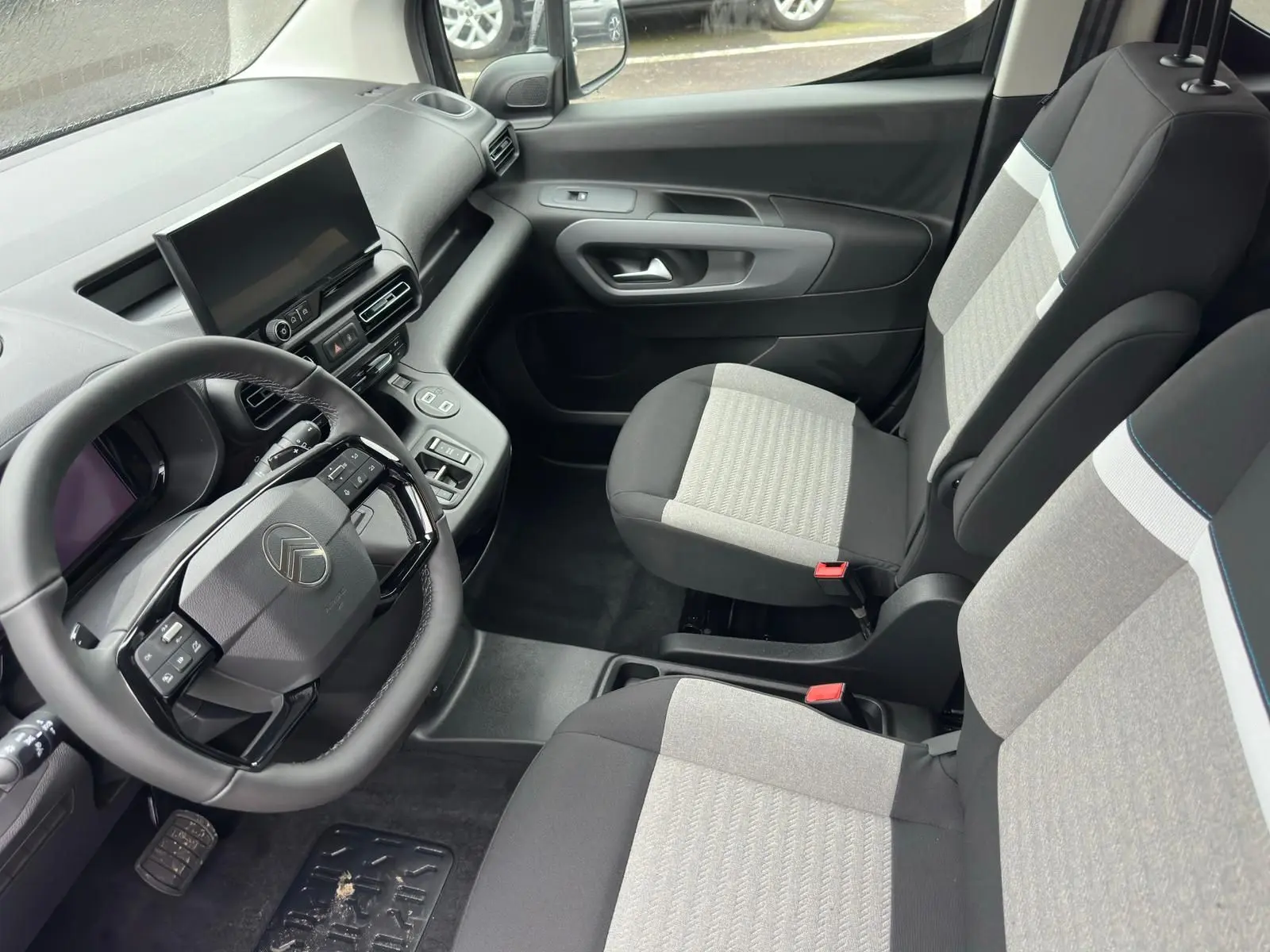 Vue intérieure côté conducteur du Citroën Berlingo 2025 avec sièges bicolores gris et noir et tableau de bord moderne.