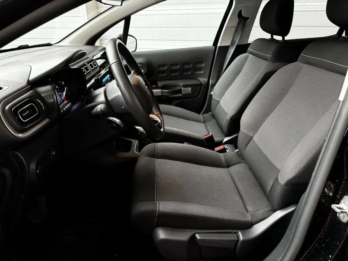 Vue intérieure côté conducteur de la Citroën C3 noire 2024, avec sièges tissu gris et tableau de bord moderne.