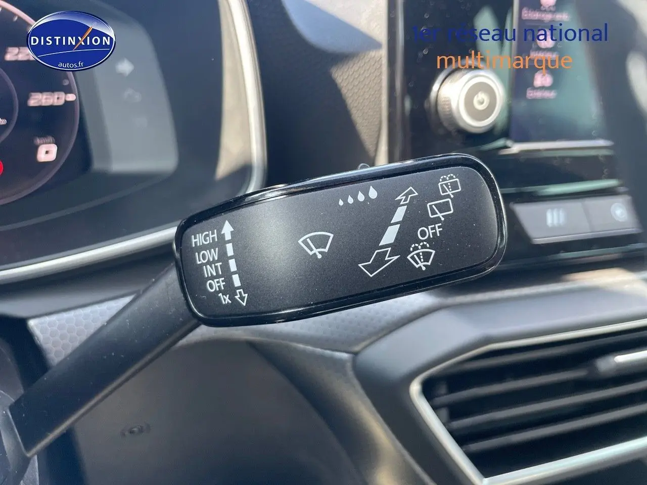 Gros plan sur la commande d'essuie-glace du SEAT LEON IV gris magnétique, avec tableau de bord et écran tactile en arrière-plan.