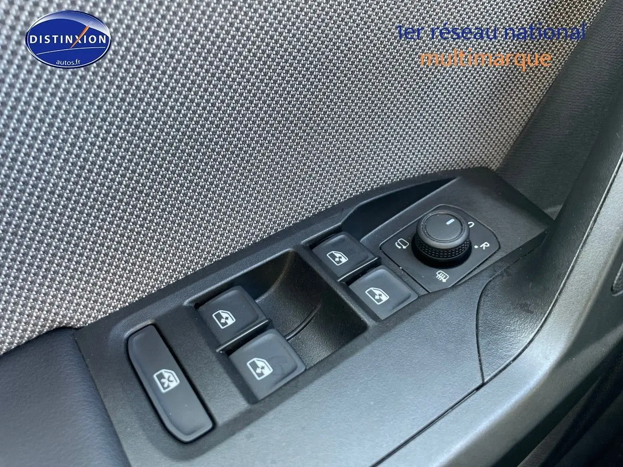 Gros plan sur les commandes des vitres électriques et rétroviseurs côté conducteur d'une SEAT Leon gris magnétique 2024.