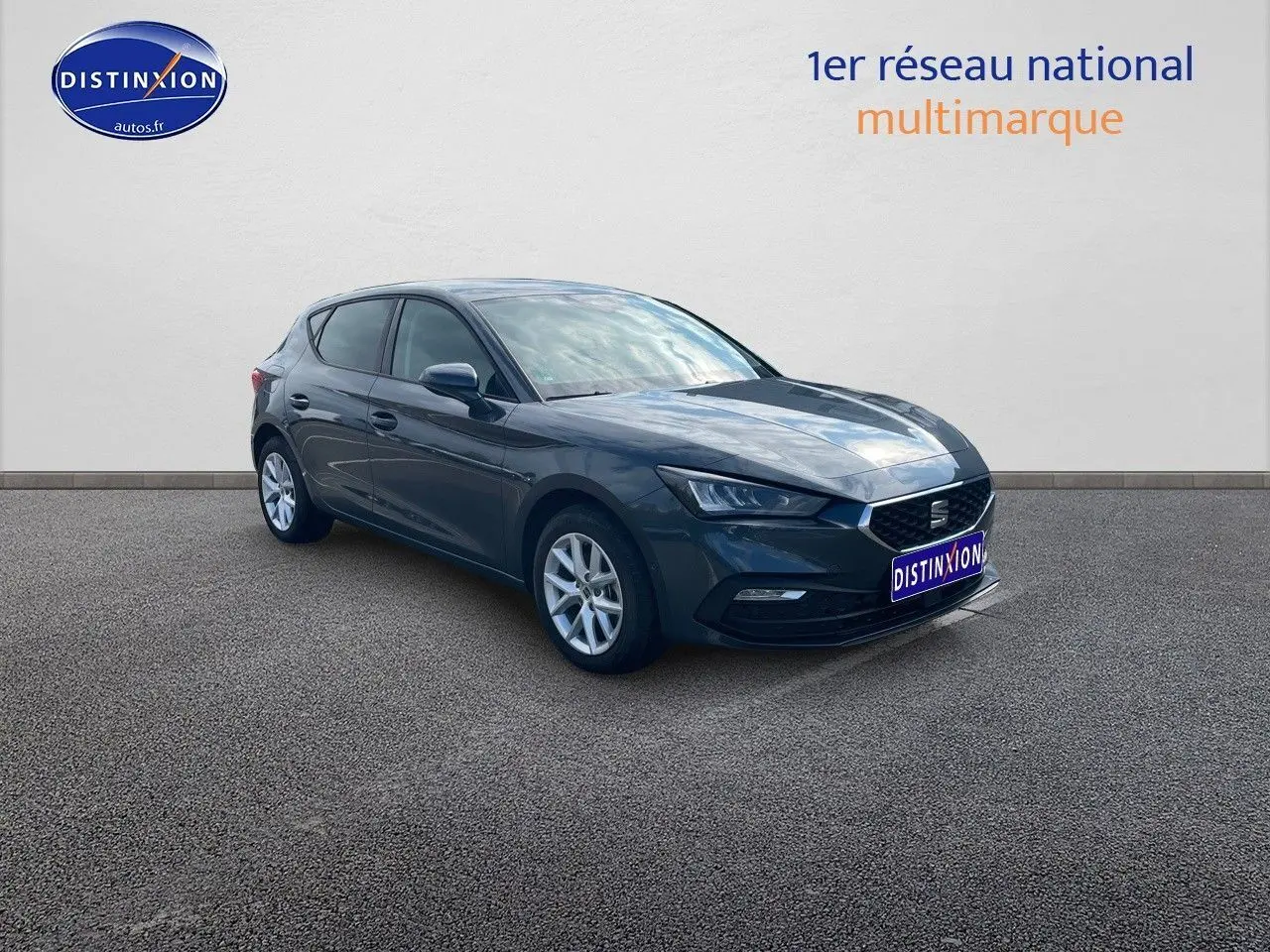 SEAT LEON IV gris magnétique métal en vue 3/4 avant droit, avec jantes argentées et phares LED allumés.