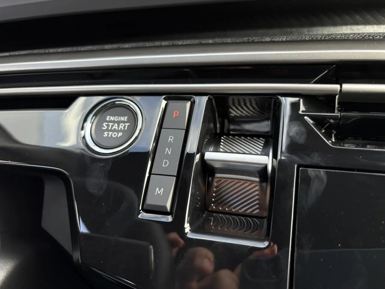Gros plan sur la console centrale noire brillante du Peugeot 5008 Hybrid avec bouton start/stop et sélecteur de boîte auto.