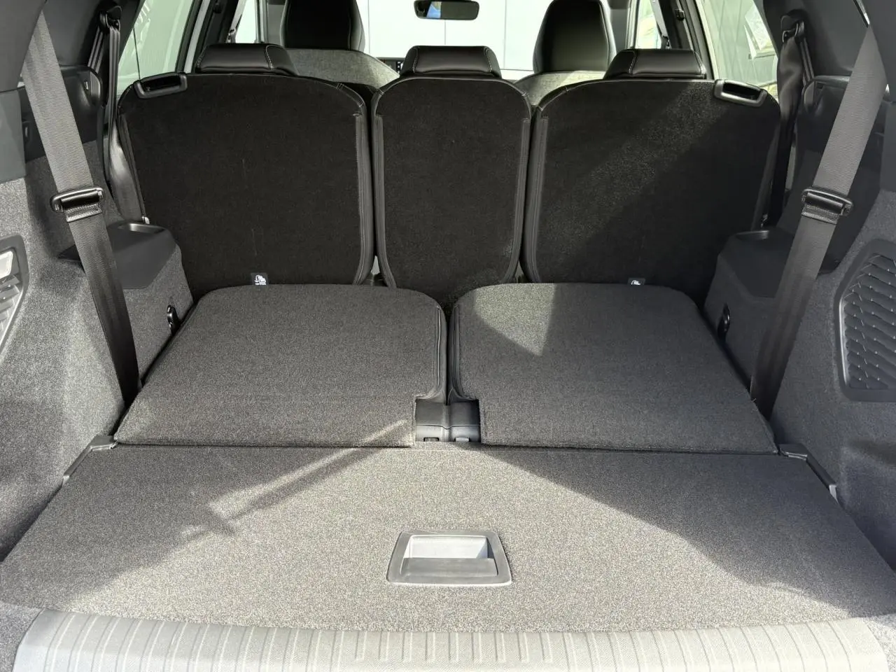 Coffre du Peugeot 5008 Hybrid blanc vu de l'arrière avec banquette arrière rabattue pour un grand espace de chargement.