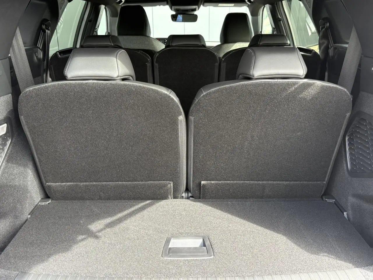 Coffre ouvert vu de l'arrière du Peugeot 5008 blanc Okénite avec banquette 3e rang rabattue.