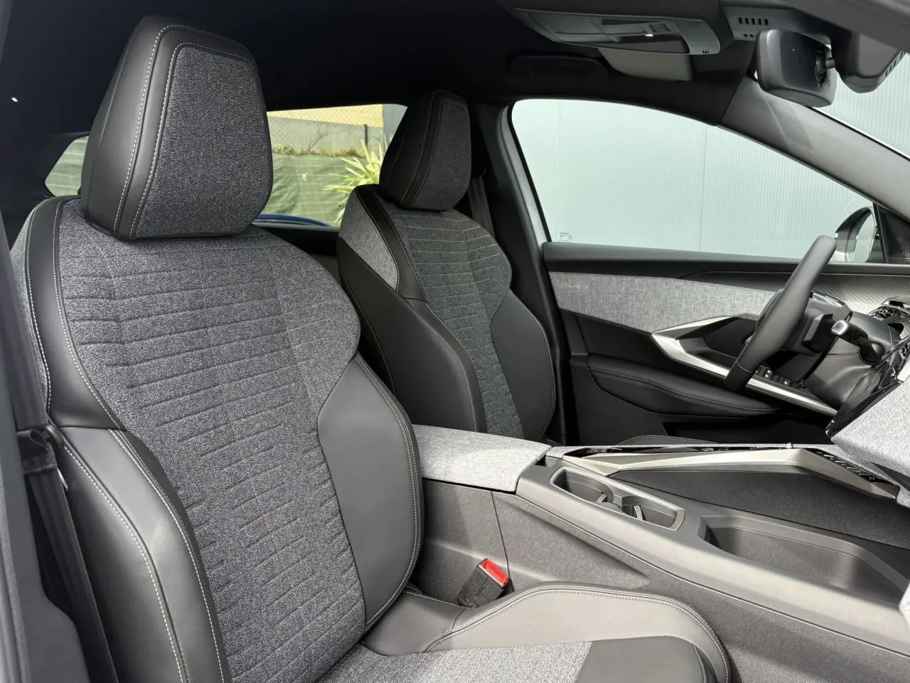Vue intérieure côté conducteur du Peugeot 5008 Hybrid 145 e-DSC6 Allure 7 places, sièges tissu gris et cuir noir, tableau de bord moderne.