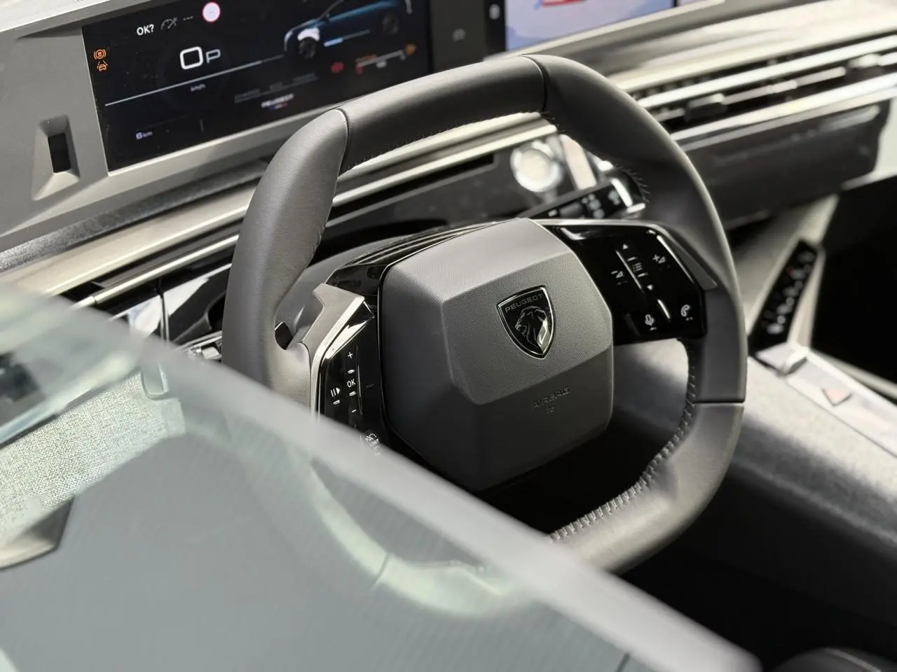 Gros plan sur le volant cuir noir et le tableau de bord numérique du Peugeot 5008 Hybrid 145 e-DSC6 Allure 2025.