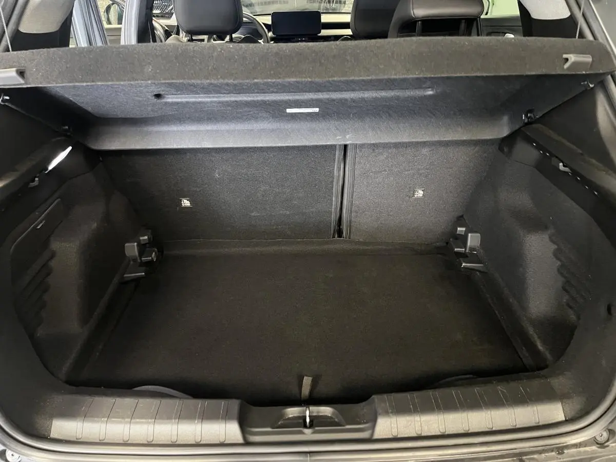 Coffre ouvert du Jeep Avenger gris 2024, vue intérieure arrière montrant l'espace de chargement et la banquette rabattable.