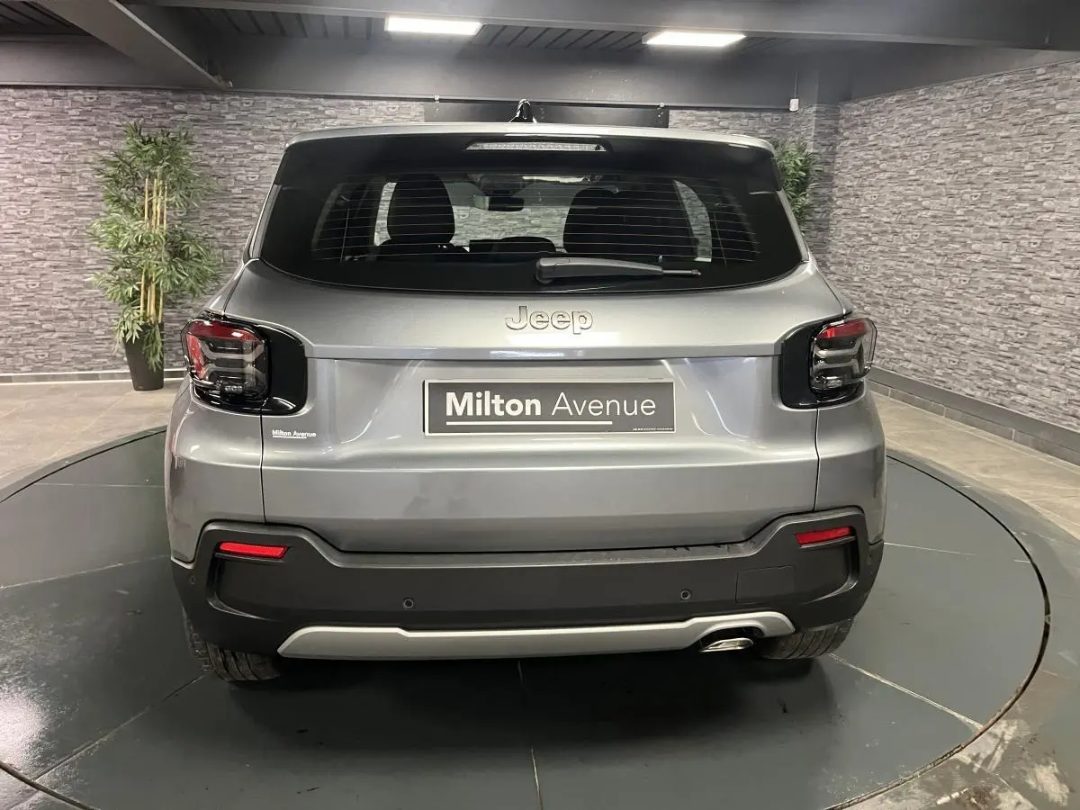 Vue arrière d'un Jeep Avenger gris métallisé 2024 avec feux arrière sombres et plaque Milton Avenue.
